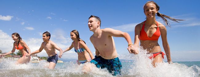En gruppe unge mennesker griner, mens de løber gennem havet under en LISA! sprogrejse i Sliema