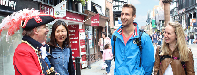 Drei Kursteilnehmer an der Sprachschule in Chester reden in der Stadt mit einem Stadtführer in Kostüm
