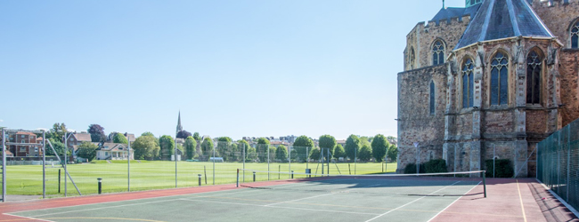 Gebäude des Clifton College in Bristol mit Tennisplätzen im Vordergrund und weiteren Sportplätzen