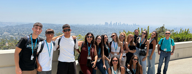 Schüler stehen vor dem Panorama von Los Angeles mit Häusern in den Hügeln und blauem Himmel