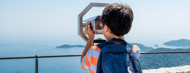 Ein Junge schaut durch ein Fernrohr aufs Meer bei einer Sprachreise in Nizza-Campus